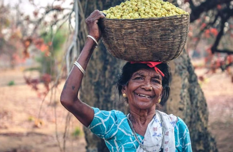 A basketful of mahua flowers brings a smile to a woman in Budhiarmari village in Chattisgarh state, India, India, Nov. 13, 2020. | Thomson Reuters Foundation/Purushottam Thakur