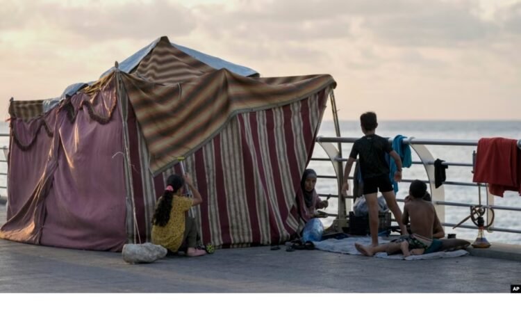 A displaced family, fleeing the Israeli airstrikes in the south, sits next to their tent on Beirut's corniche, Lebanon, Oct. 14, 2024.